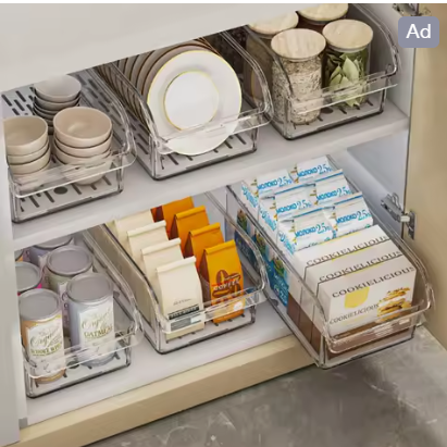 Clear organizer bins holding kitchen and pantry supplies inside a cabinet
