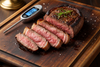 Perfectly cooked medium-rare steak sliced open with meat thermometer beside it