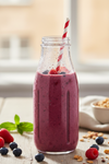 Vibrant berry smoothie in wine-bottle shaped personal blender with condensation